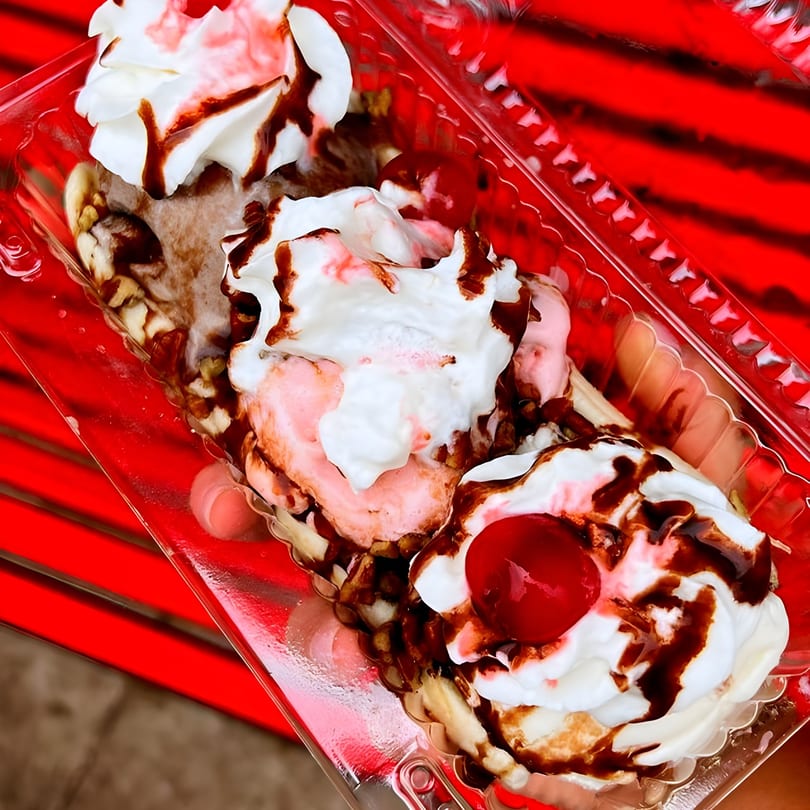A banana split with three scoops of ice cream, whipped cream, chocolate syrup, and cherries.
