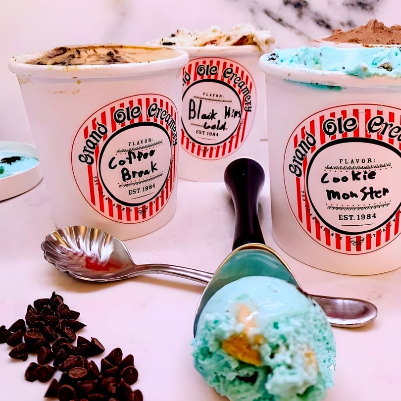 Three Grand Ole Creamery pints of ice cream, a scoop of blue ice cream, and chocolate chips.